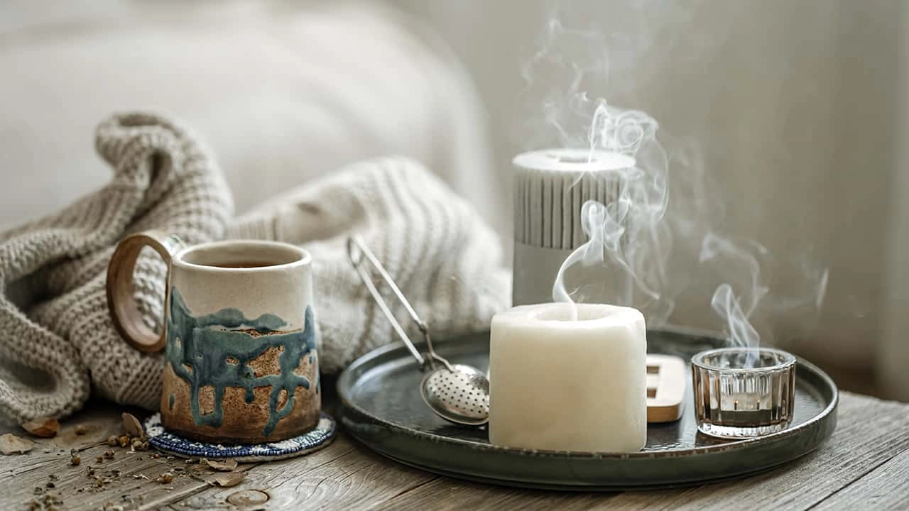 cozy-composition-with-ceramic-cup-candles-knitted-element-blurred-background - Saintdeland Fragrance