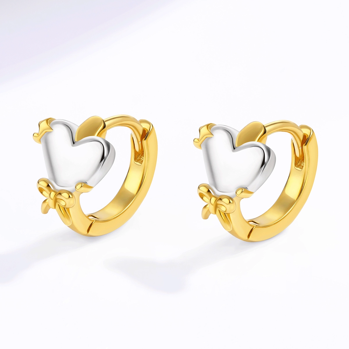 Primo piano di orecchini a cerchio a forma di cuore in vermeil d'oro con dettagli a fiocco e stella, realizzati da un produttore di orecchini personalizzati. - Zhefan Jewelry