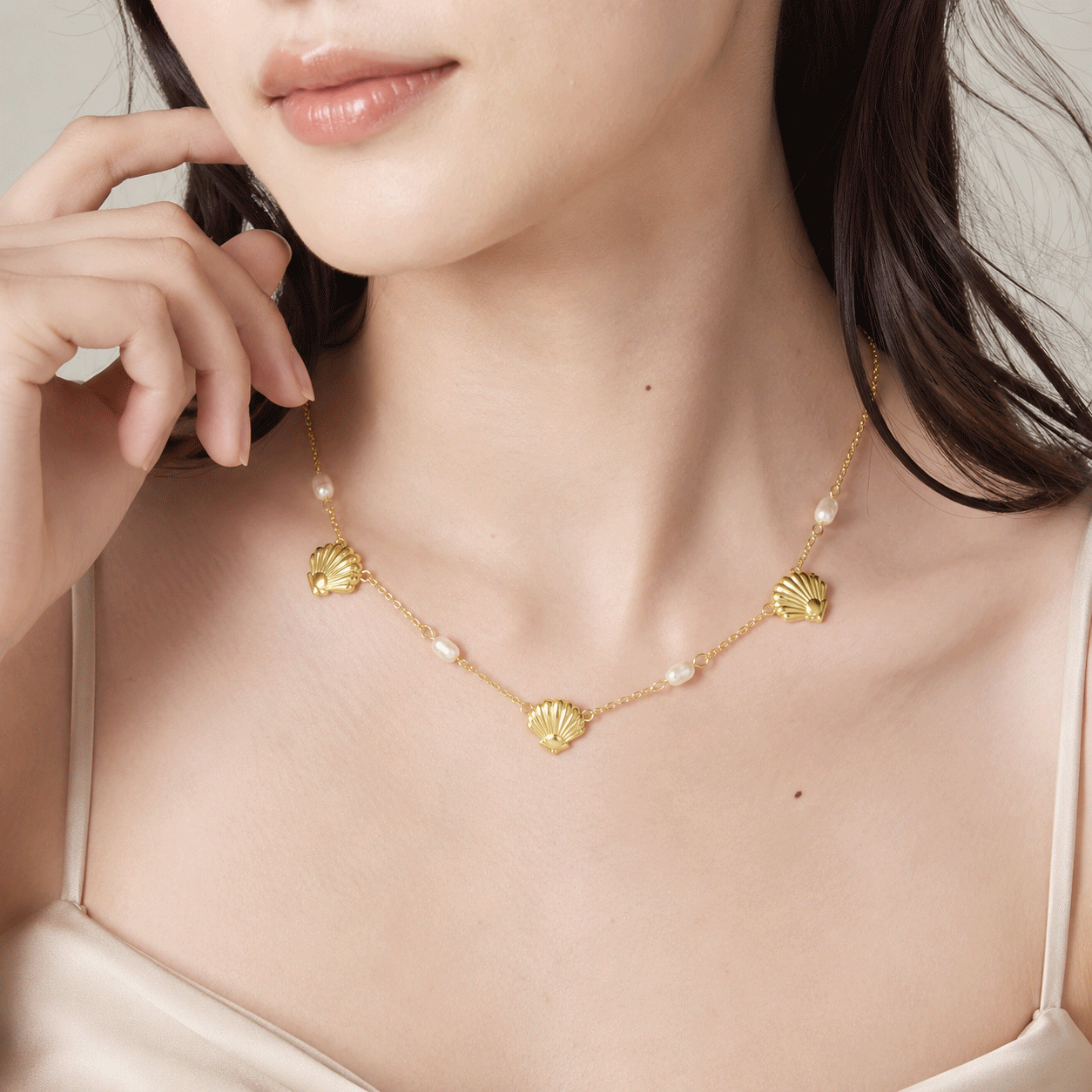 Modella indossa una collana di perle e conchiglie color oro per la presentazione B2B di una collezione di gioielli.