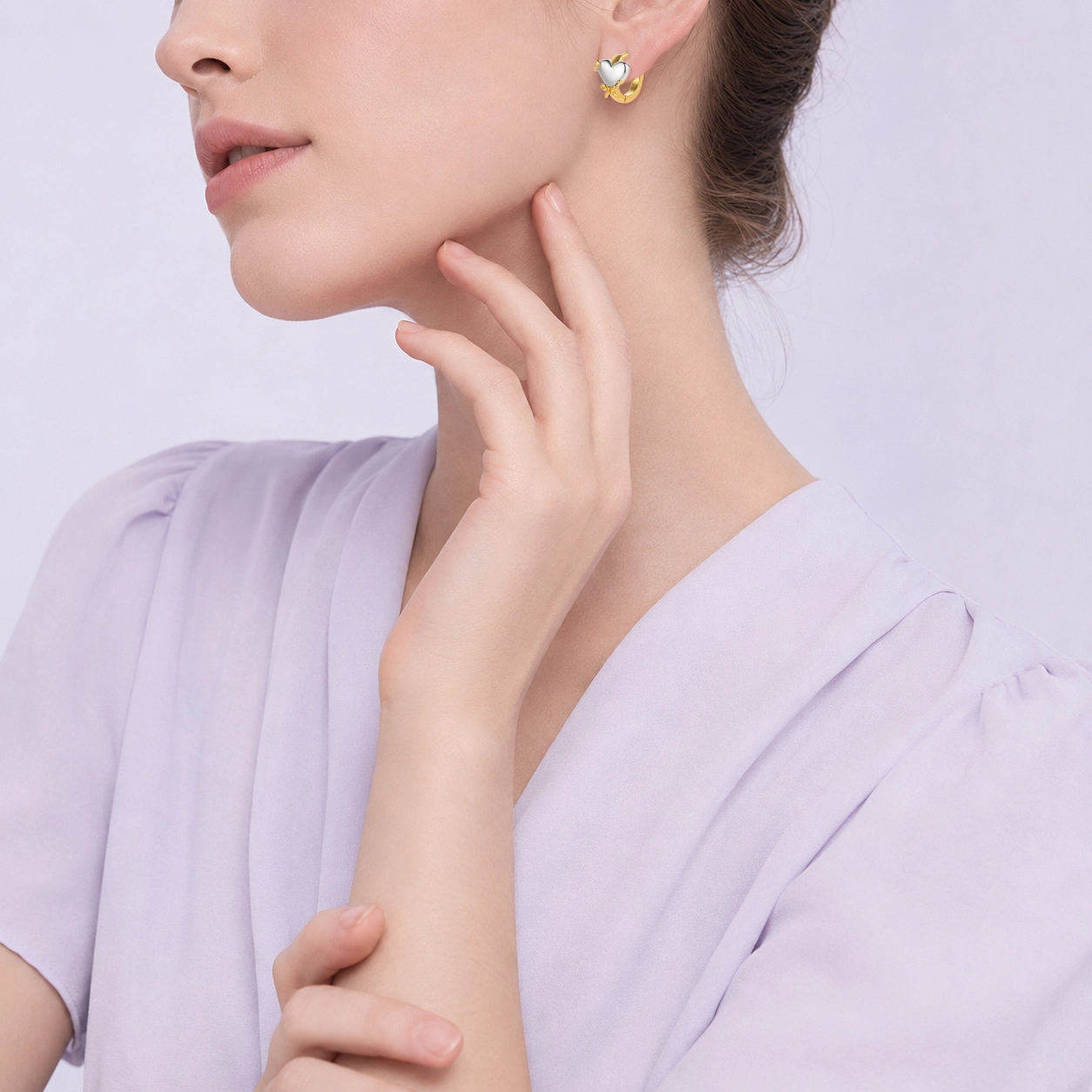 Vista laterale di una modella che indossa orecchini a cerchio a forma di cuore, disegnati per le collezioni del marchio di gioielli personalizzati Zhefan Jewelry.