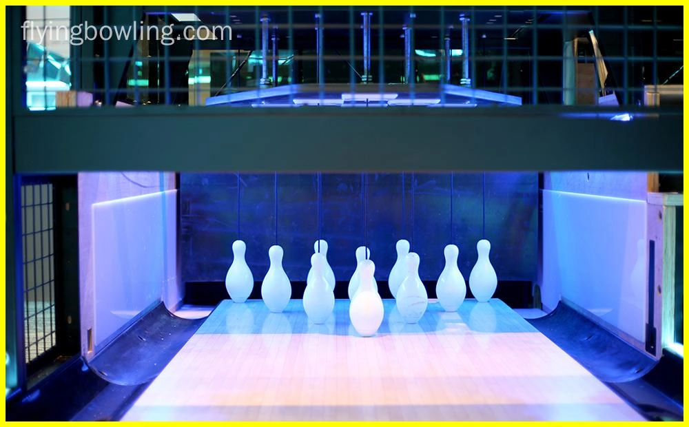 Flying - A bowling alley with the pins set up and ready to be bowled at. The pins are illuminated by a blue light.