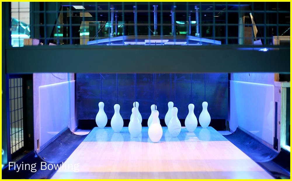 Fly Bowling - A bowling alley with the pins set up and ready to be bowled at. The pins are illuminated by a blue light.
