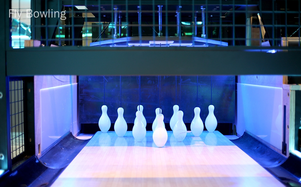 Fly Bowling - nouvelles pistes de bowling Bowling à la mouche – Une piste de bowling où les quilles sont installées et prêtes à être lancées. Les quilles sont éclairées par une lumière bleue.