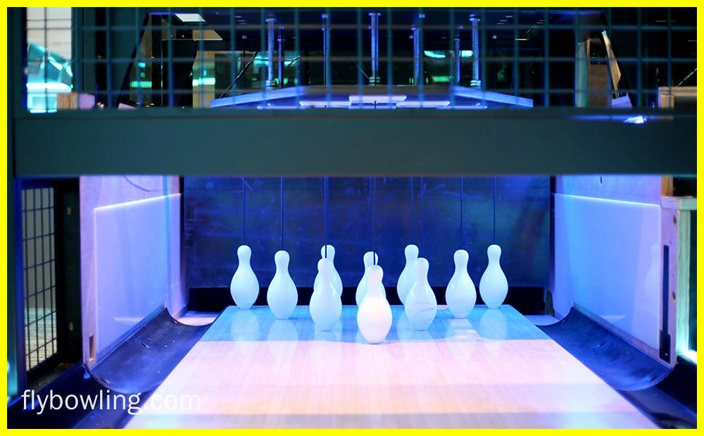 Flying Bowling - A bowling alley with the pins set up and ready to be bowled at. The pins are illuminated by a blue light.