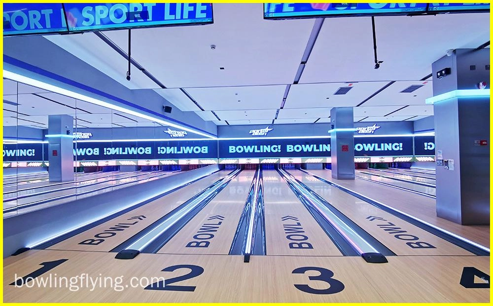 Flying Bowling - Imagem de uma pista de boliche com quatro pistas. As pistas são feitas de madeira e têm uma superfície brilhante e encerada. Os pinos são colocados no final de cada pista. Há uma tela grande no final da pista que mostra a pontuação dos jogadores.