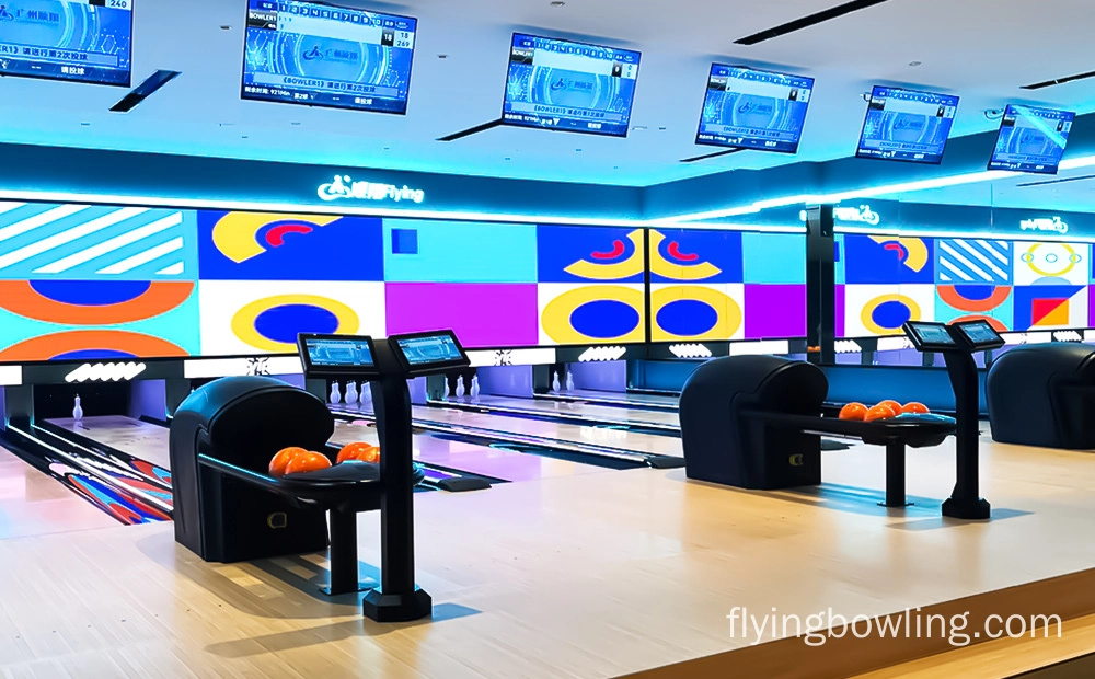 A bowling alley with two lanes and a colorful geometric design on the back wall.  Two bowling balls are sitting on the return of one lane.