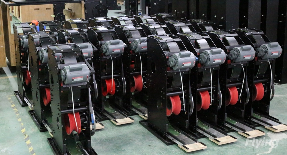A row of black String Pinsetters with red wheels sit on the floor in a warehouse.