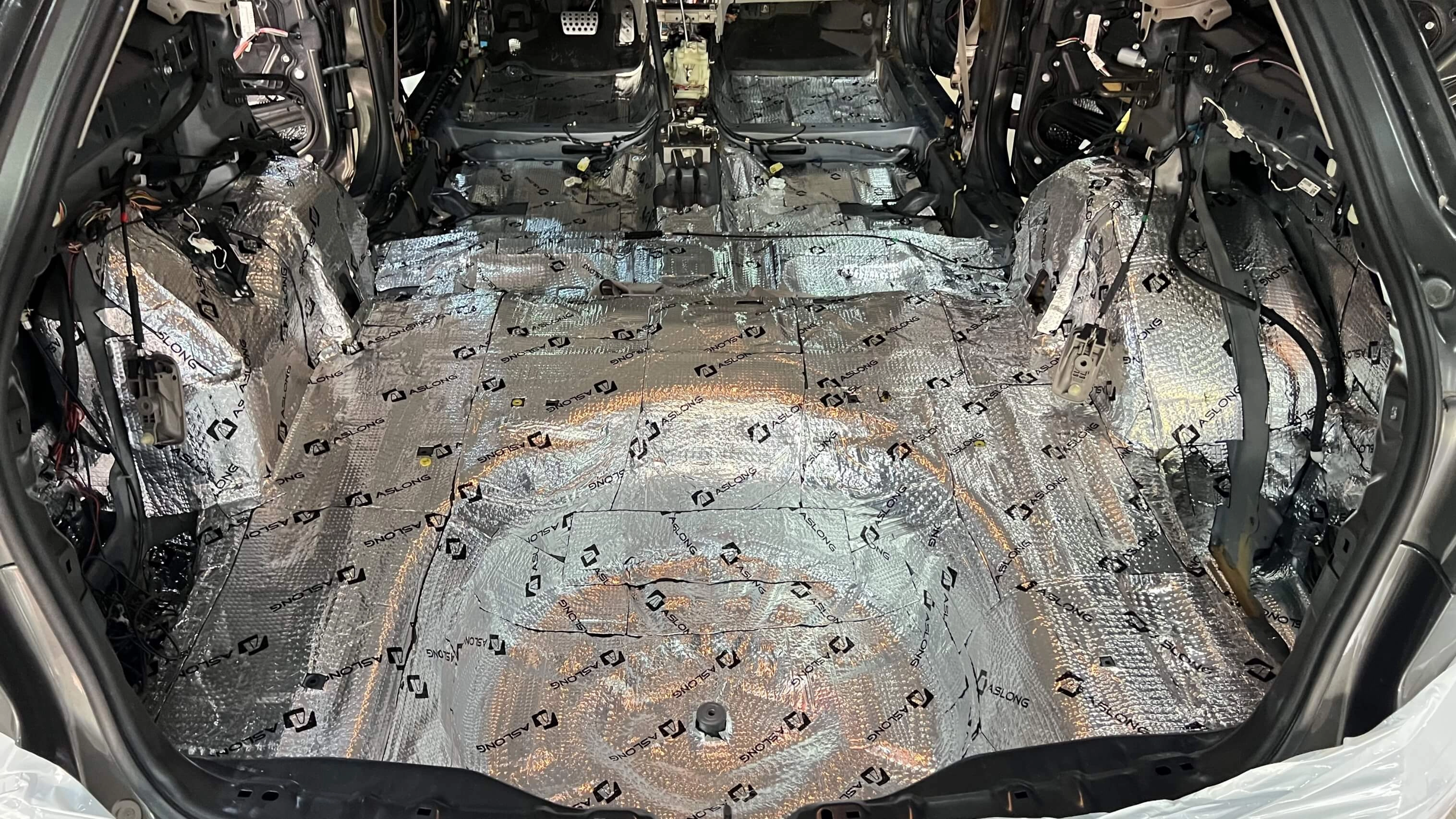 Interior of a car stripped and lined with sound dampening material.