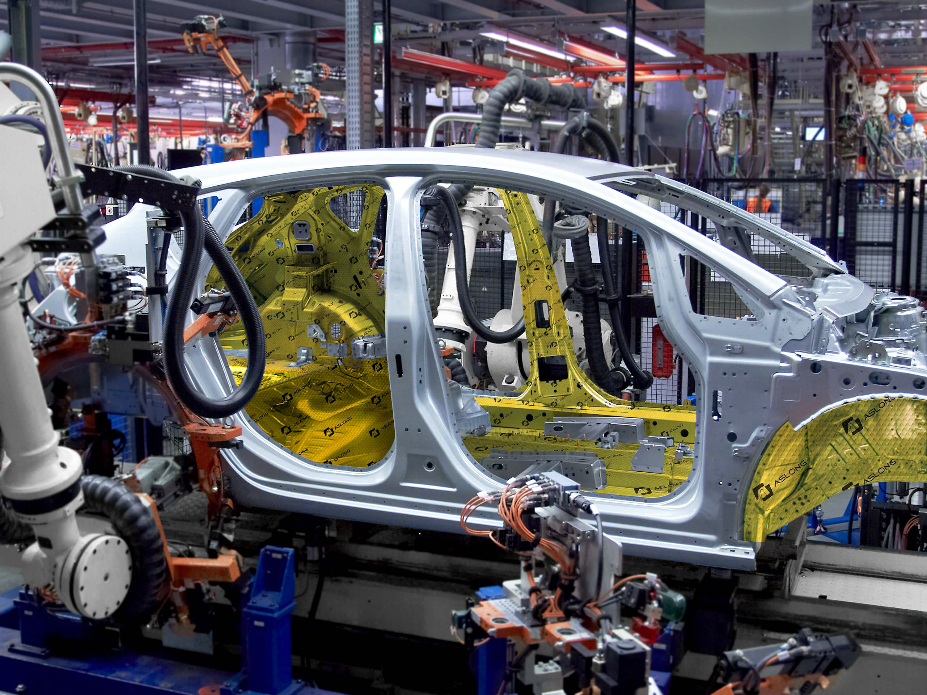 Automated robotic arms assembling a car chassis in a factory.
