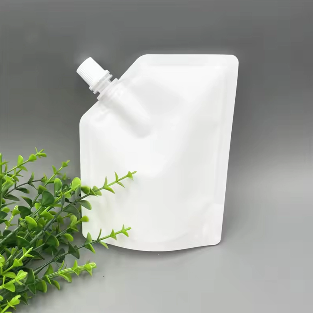 White spout pouch with a white cap next to greenery.