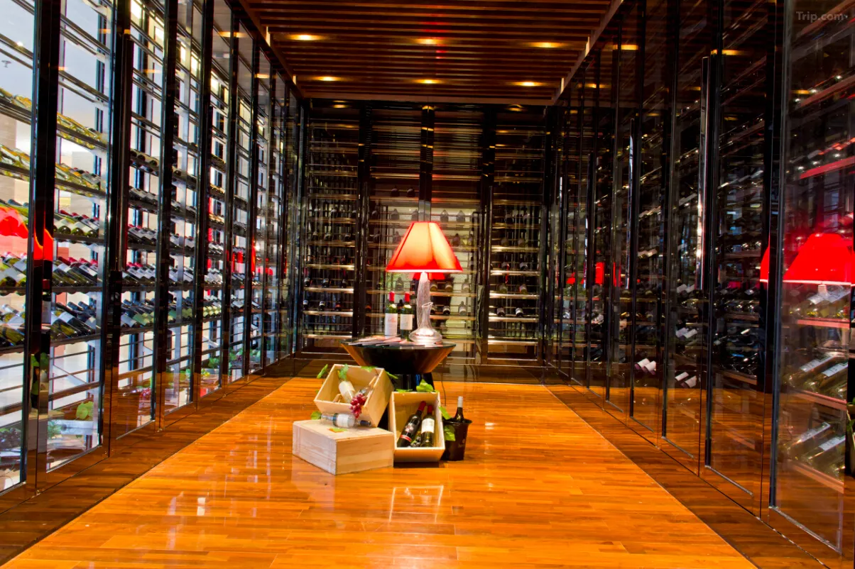 Modern wine cellar with floor-to-ceiling glass racks, wooden floors, and a red lamp display.