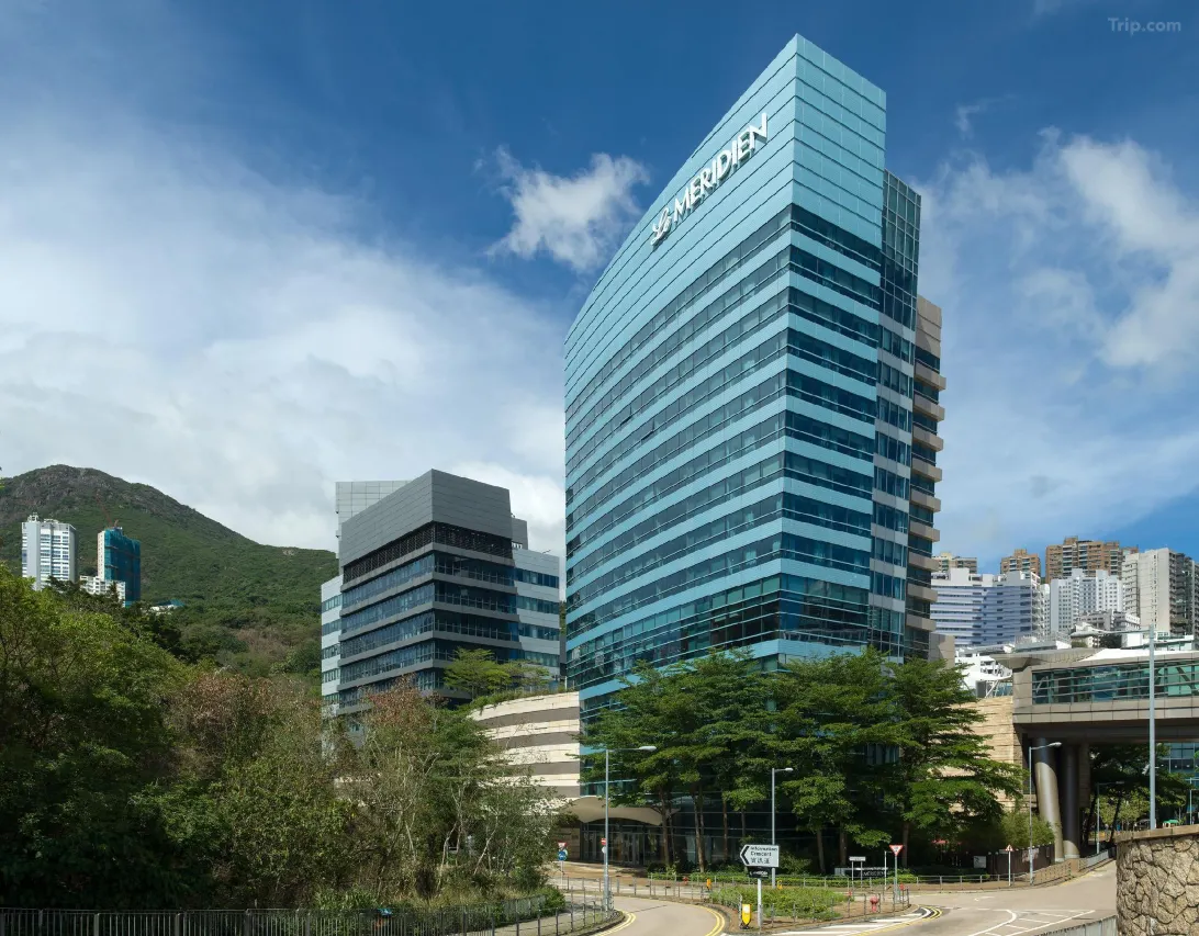 Exterior of Le Méridien hotel, a modern blue glass skyscraper in Hong Kong.