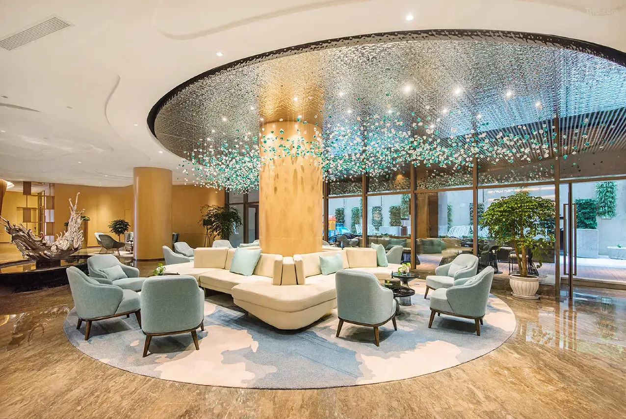 Modern hotel lobby with circular seating and unique hanging light fixture.