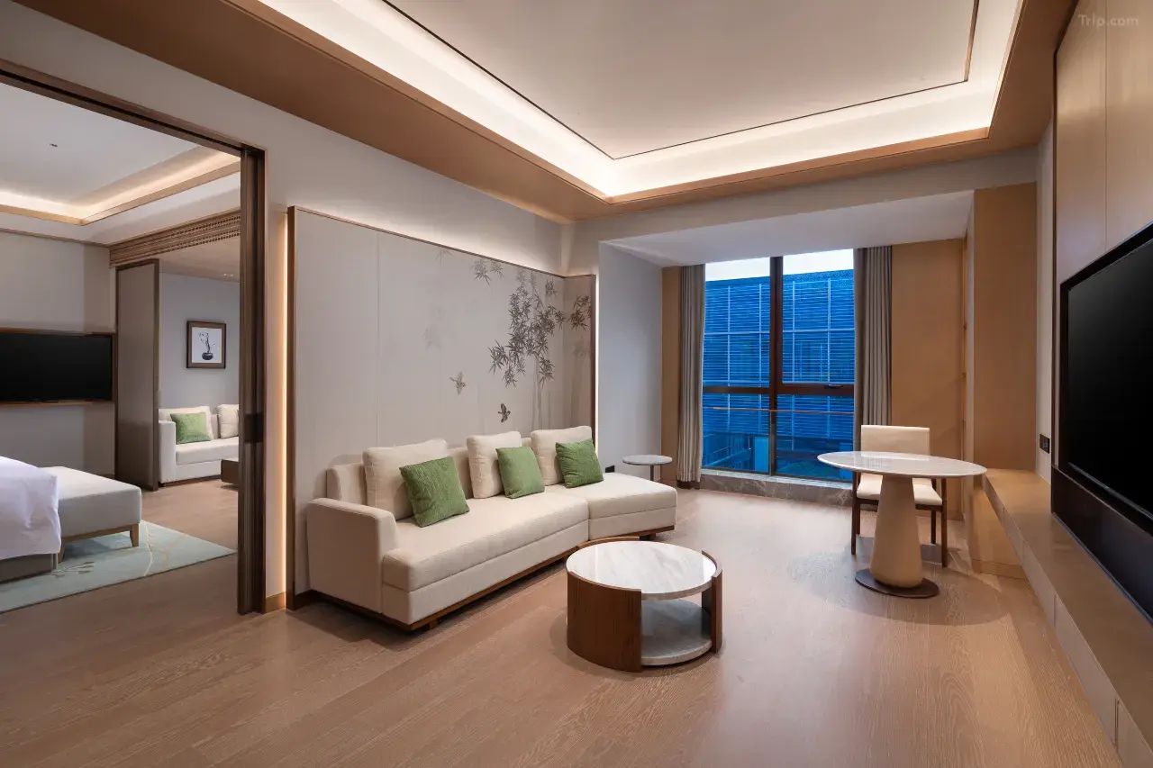 Modern hotel suite living room with a white sofa and green pillows.