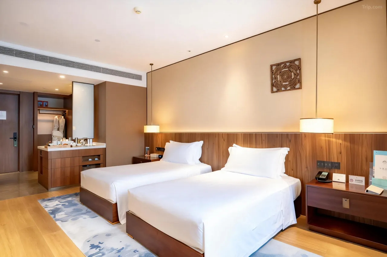 Twin beds in a modern hotel room with wooden accents and white bedding.