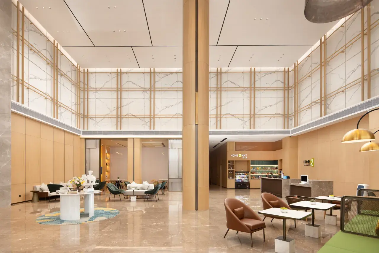 Modern hotel lobby with high ceilings, marble walls, and wood accents.