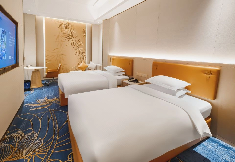 Modern hotel room with two twin beds, orange headboards, and blue floral carpet.