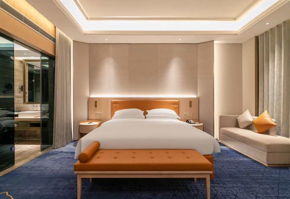 Modern luxury hotel bedroom with orange accents and blue patterned carpet.