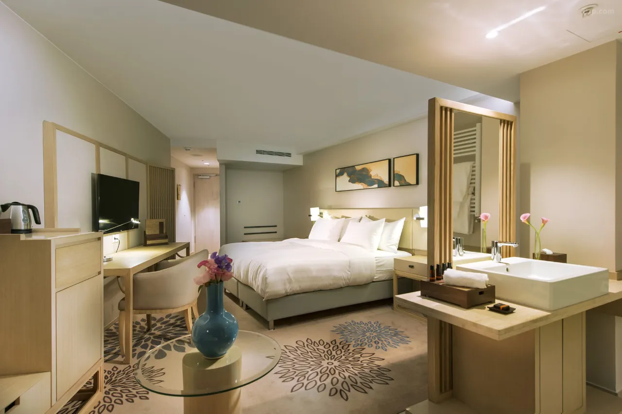 Modern hotel room with a king bed, desk, and open-concept vanity.