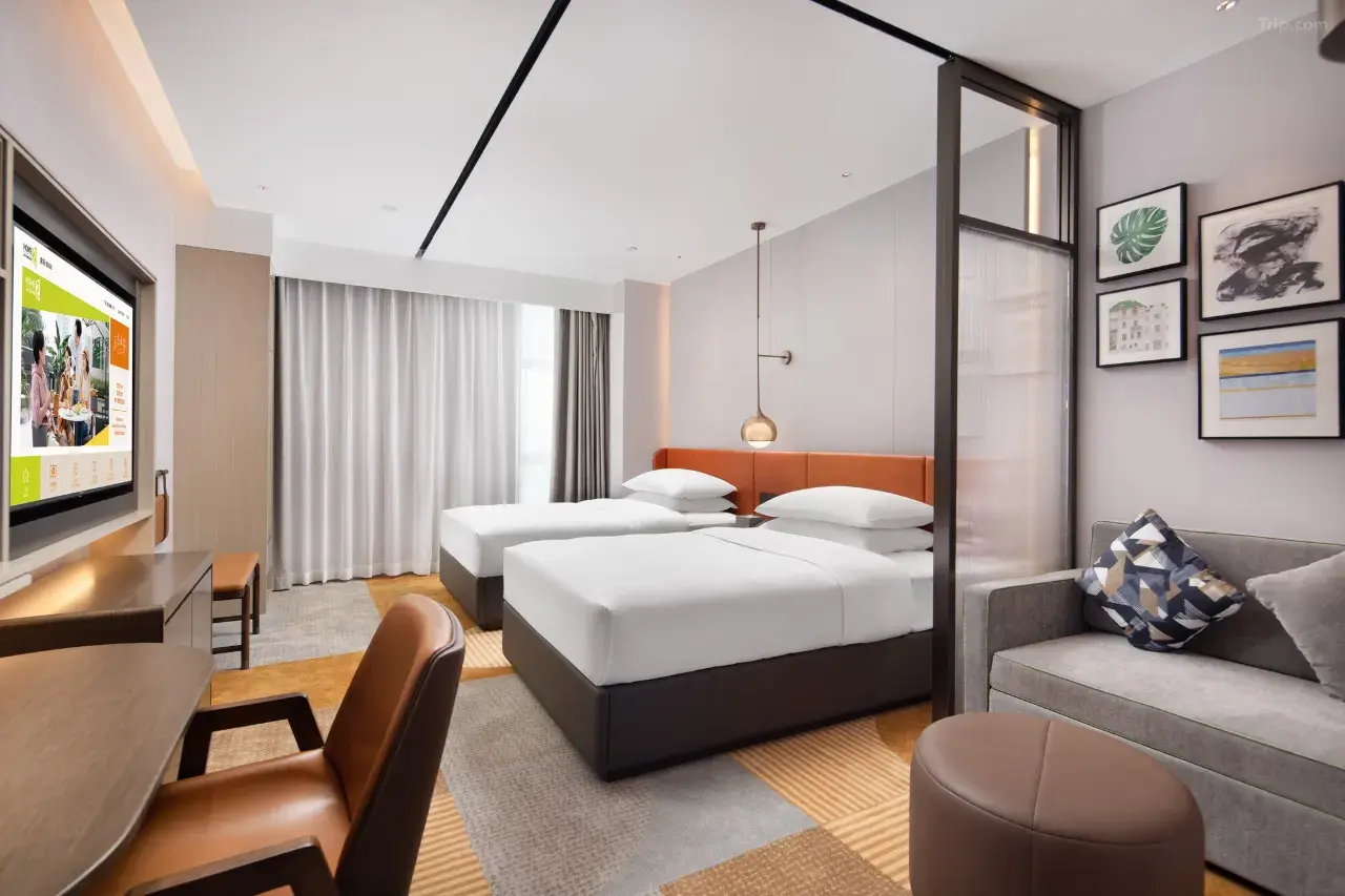 Modern hotel room with two twin beds, a desk, and a small sitting area.