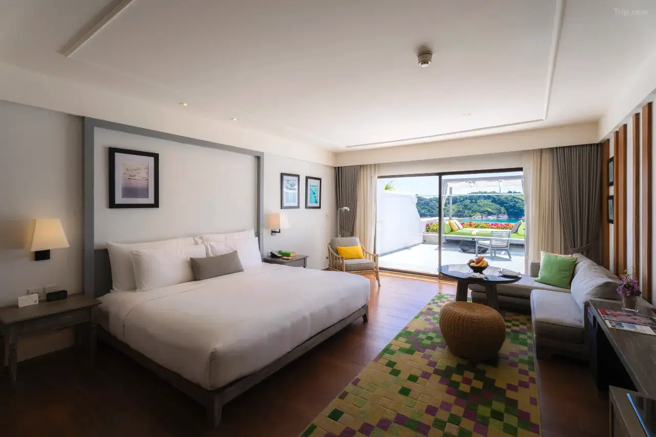 Hotel suite with king-size bed and private balcony overlooking the sea.