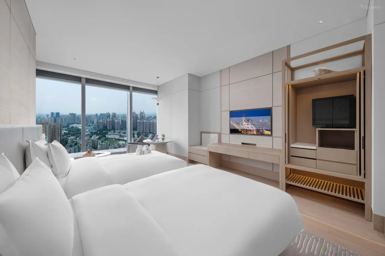 Modern hotel room with two twin beds and a panoramic city view.