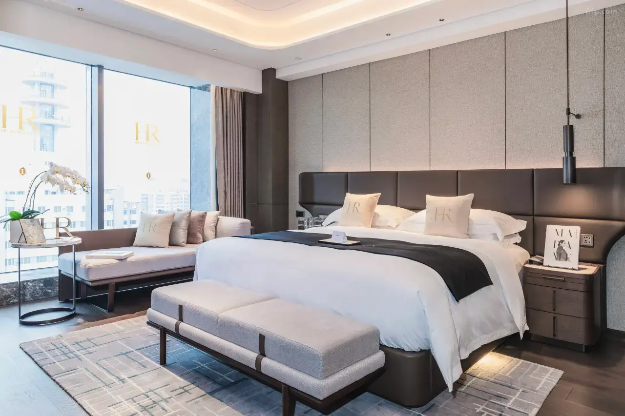 Modern luxury hotel bedroom with a large bed, city view, and elegant decor.