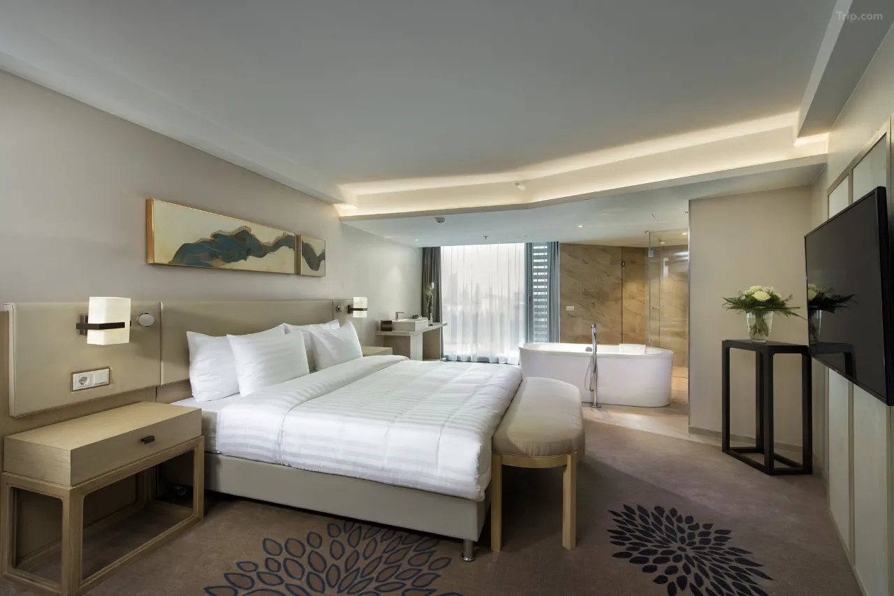 Modern hotel suite with a king bed and an open-concept bathtub.