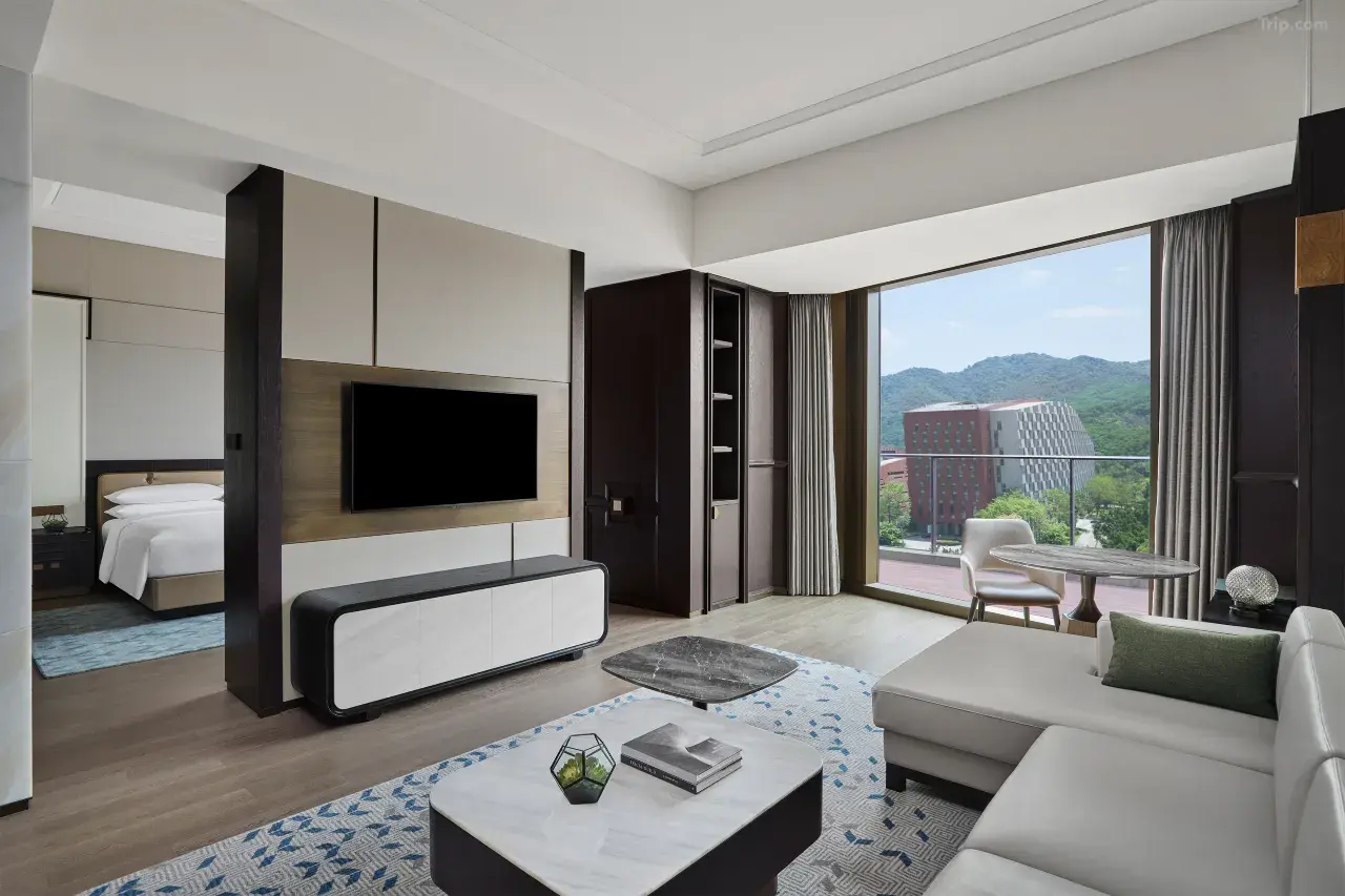 Modern hotel suite with a living area, floor-to-ceiling windows, and mountain view.