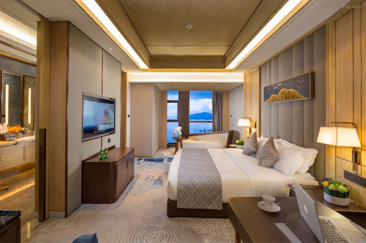 Modern luxury hotel suite with a king bed, ocean view, and wooden accents.