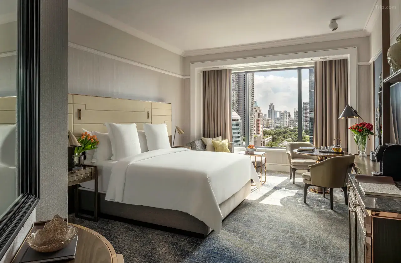 Modern luxury hotel room with a city view and white bedding.