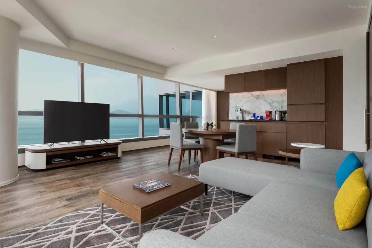 Modern hotel suite with ocean views, living area, and kitchenette.