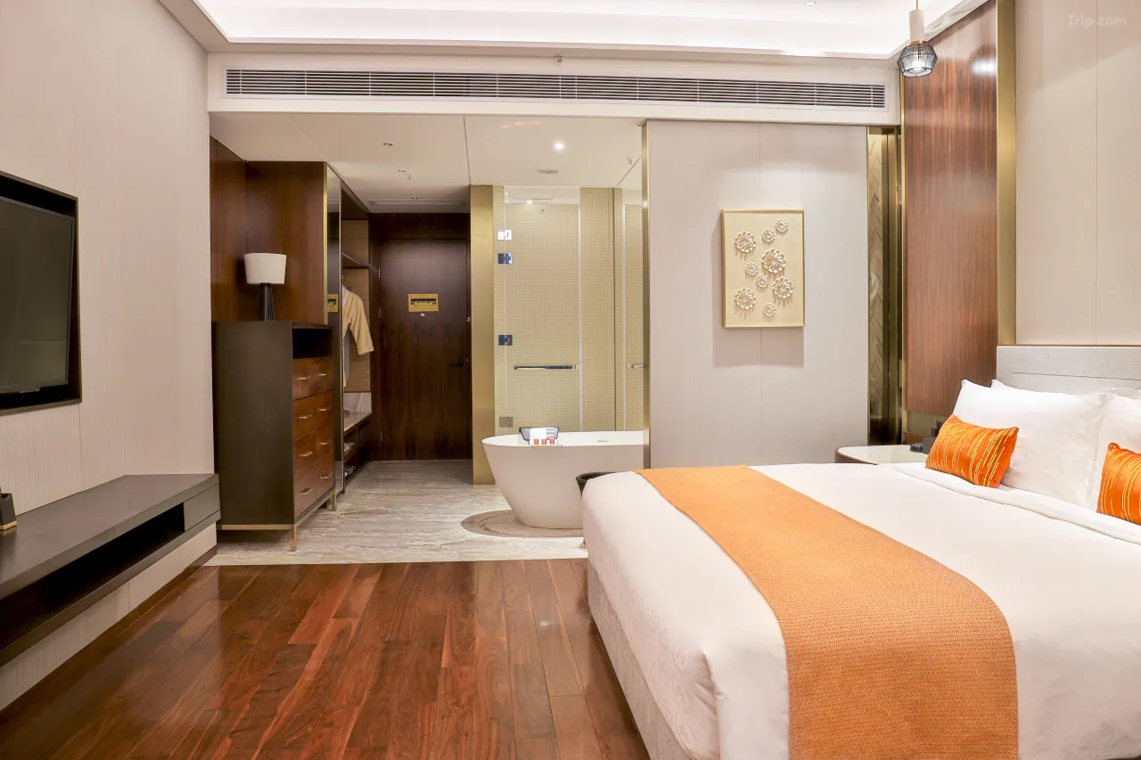 Hotel room interior with bed, open bathroom, and wood accents.