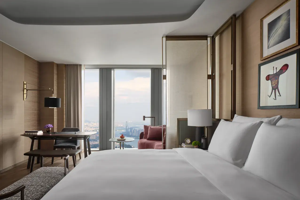 Modern luxury hotel bedroom with a city view and elegant wood paneling.