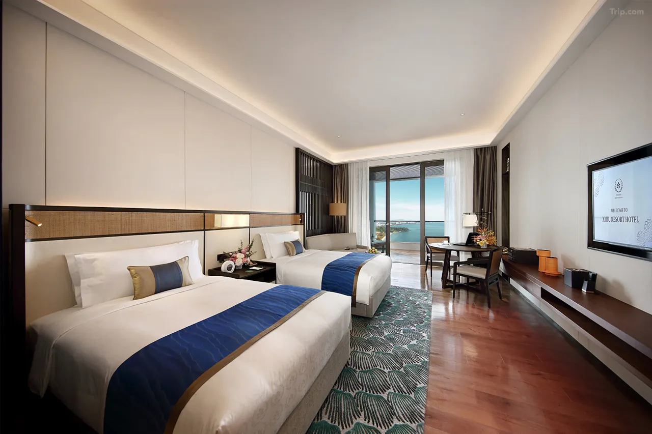 Hotel room interior with two beds, balcony, and ocean view.