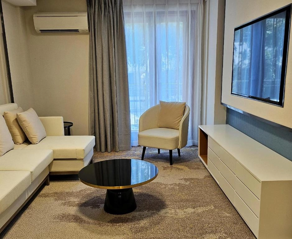 Modern living room with a white sectional sofa, black coffee table, and TV.
