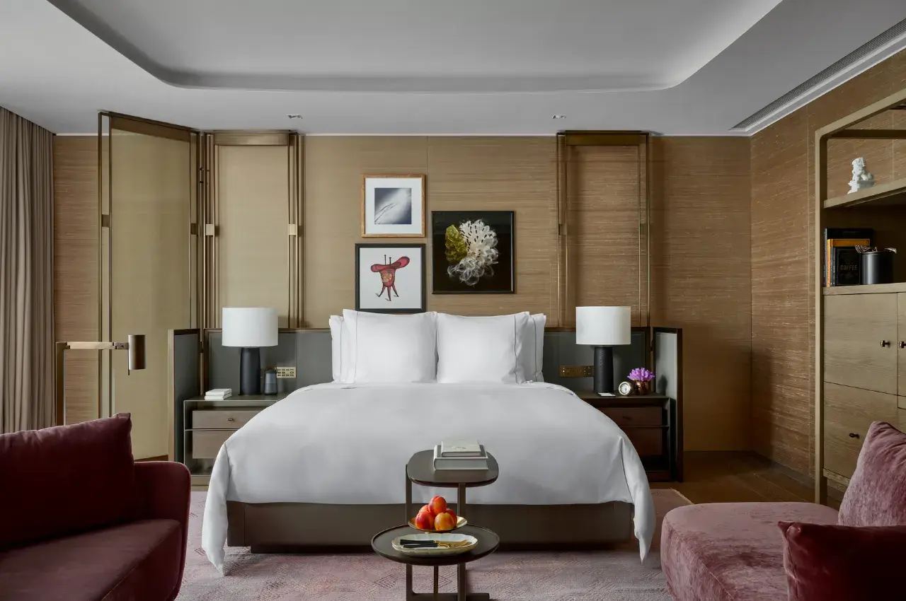 Modern luxury hotel bedroom with white bedding and warm wood paneling.