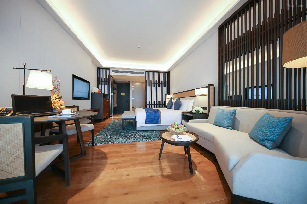 Hotel room interior with a desk, bed, sofa, and wooden accents.