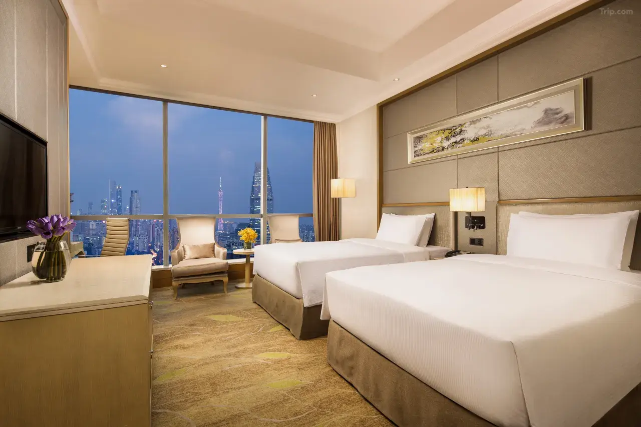 Hotel room with two beds, city skyline view, and modern decor.