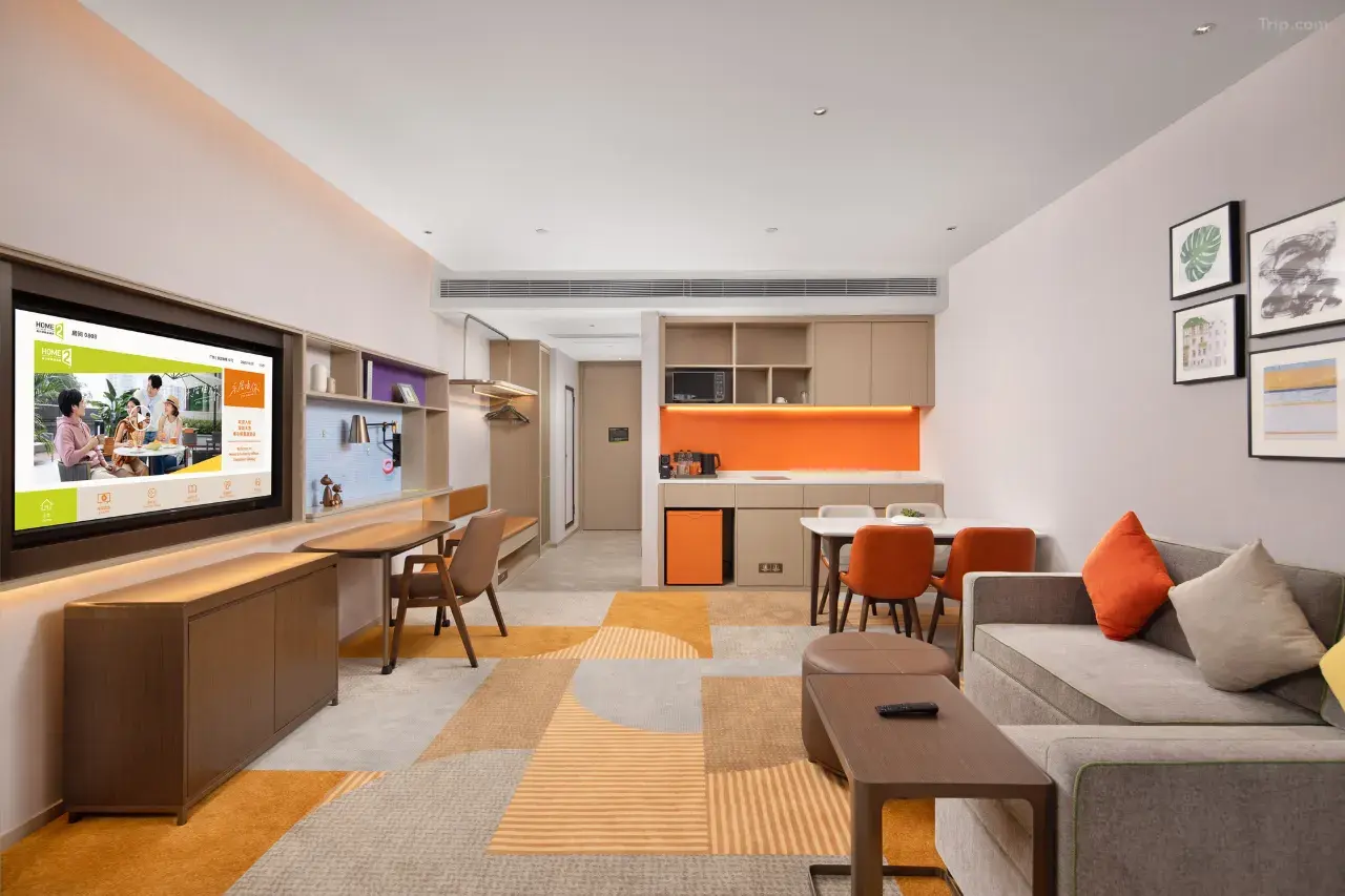 Modern hotel suite with living area, desk, and kitchenette