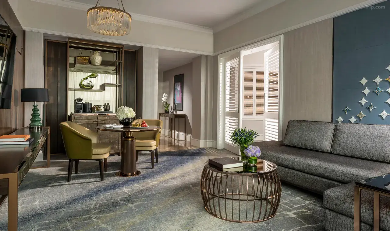 Modern luxury hotel suite with a grey sofa, dining table, and elegant decor.