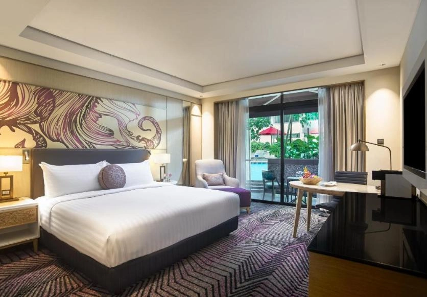 Hotel room with king-size bed, artwork headboard, desk, and balcony overlooking the pool.