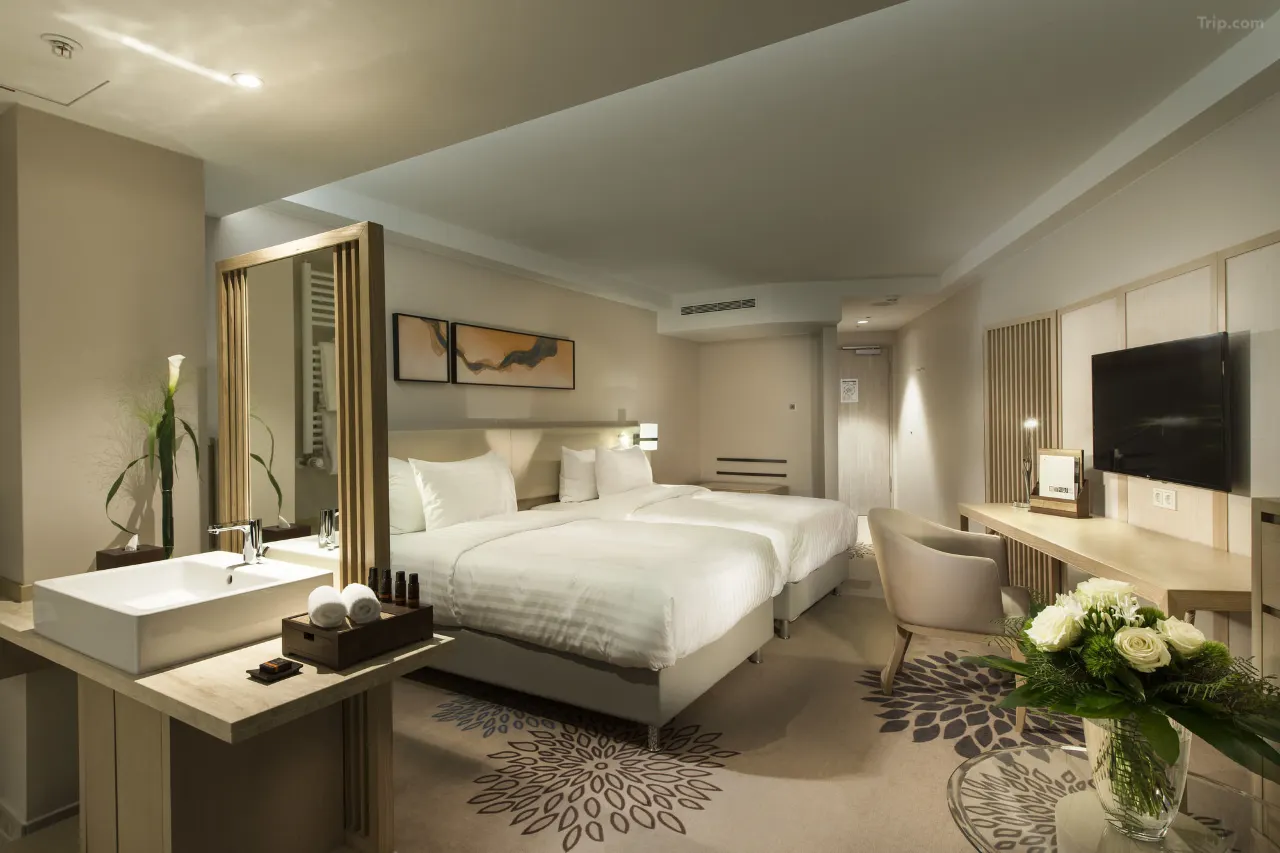 Modern hotel room with two twin beds, a vanity sink, and a work desk.