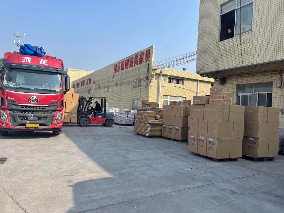 Furniture factory loading area with a red truck, forklift, and stacked boxes.