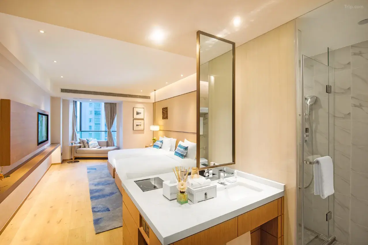 Spacious hotel room with two beds, a vanity, and a shower.