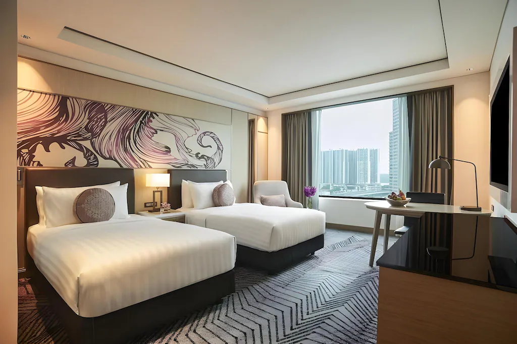 Hotel room with two twin beds, modern decor, and city view.