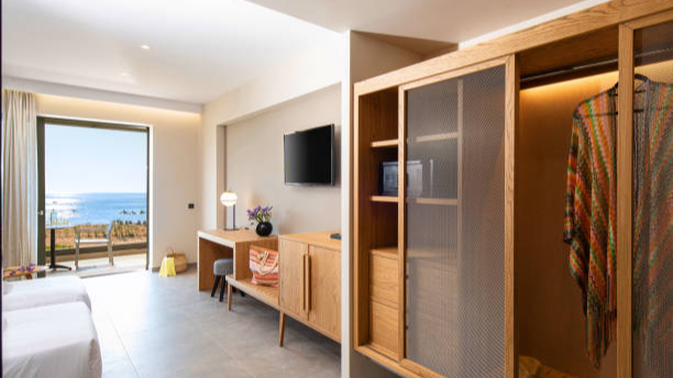 Hotel room wardrobe with wood finish, mesh doors, and ample storage.