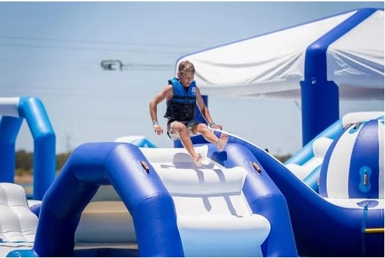 Boy in life vest sliding down inflatable water slide at a water park.