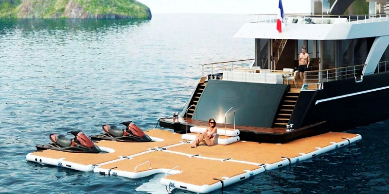 Imagem de um parque aquático inflável flutuante com uma variedade de recursos, incluindo um barco para festas com escorregador, uma parede de escalada e um trampolim.