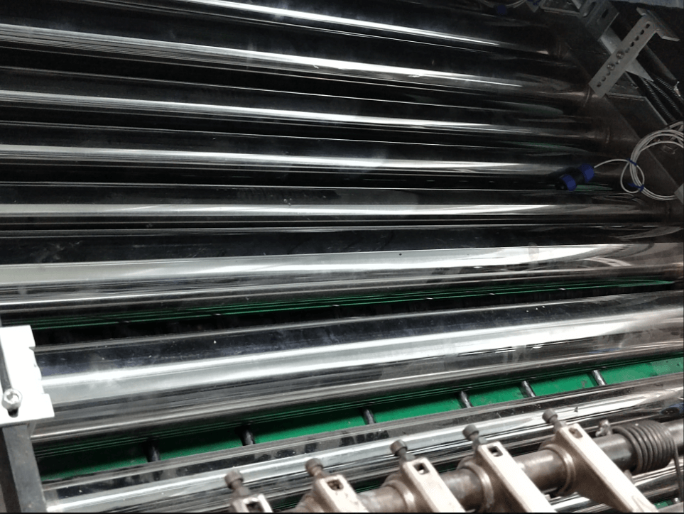 Close-up of shiny metallic rollers on a machine, likely part of an industrial printing or processing system.